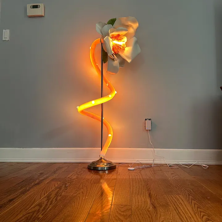 Magnolia sculptural lamp casting warm orange light on a wood floor