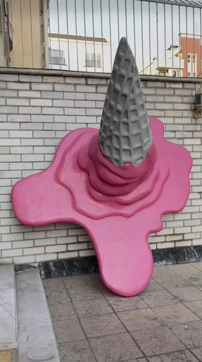 Upside-down ice cream cone sculpture melting into a pink puddle