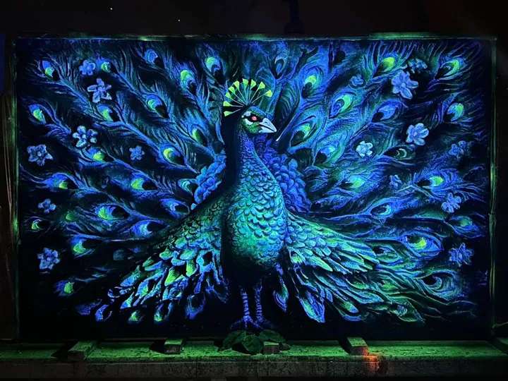 Large UV-reactive peacock relief mural glowing blue and green in the dark